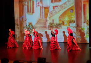 Kopciuszek - taniec hiszpański - tancerki w czerwonych, długich spódnicach z falbanami, czarnych gorsetach i trzymają czerwone wachlarze
